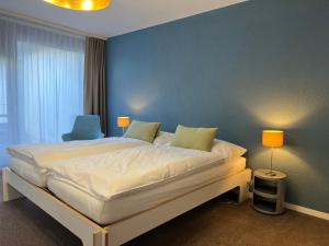 a bedroom with a large bed with a blue wall at Hotel Bad Murtensee in Murten