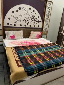 a bedroom with a bed with a plaid comforter at Udaipur Stays 2 in Udaipur
