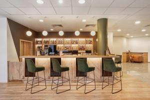 a bar with green chairs in a lobby at H+ Hotel Darmstadt in Darmstadt