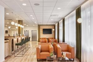 a waiting room with leather chairs and a bar at H+ Hotel Darmstadt in Darmstadt