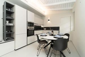a white kitchen with a table and chairs at Appartamento moderno a 2 minuti dal duomo di Como in Como