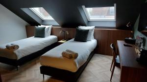 two beds in a room with two windows at Vinotel X in Tongeren