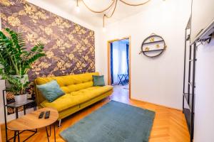 ein gelbes Sofa im Wohnzimmer mit einer Wand in der Unterkunft Modernes Appartement in Graz