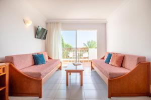 a living room with two couches and a table at Inturotel Esmeralda Garden in Cala d´Or