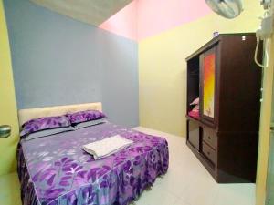 a bedroom with a purple bed and a dresser at RIZQI HOMESTAY Sungai Siput with Wifi! Islamic Guest Only! in Kampong Rimba Panjang