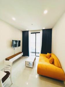 ein Wohnzimmer mit einem gelben Sofa und einem Tisch in der Unterkunft Experience Luxury Living! Spectacular 1-Bedroom Apartment in Thuan An, Binh Duong in Thuan An