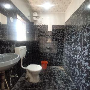 Baño de azulejos negros con aseo y lavamanos en VILLA CASA SUMANJO (3BHK), en Calangute