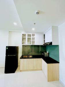 eine Küche mit einem schwarzen Kühlschrank und weißen Schränken in der Unterkunft Experience Luxury Living! Spectacular 1-Bedroom Apartment in Thuan An, Binh Duong in Thuan An