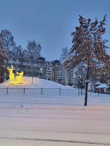 duas esculturas amarelas estão num parque coberto de neve em Arctic Apartment with own Sauna em Rovaniemi