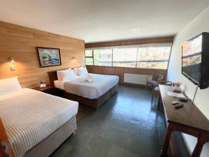 a hotel room with two beds and a flat screen tv at Hotel Costanera Pucón in Pucón