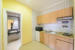 a kitchen with wooden cabinets and a sink and a mirror at Mogador Menzah Appart Hôtel in Marrakech