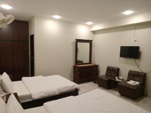 a bedroom with two beds and a mirror and a tv at Hotel Inn in Karachi