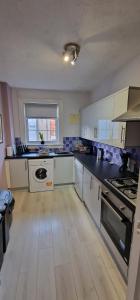 una gran cocina con armarios blancos y encimeras negras en Morris Terrace Apartment, en Stirling