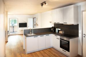 una cucina con armadi bianchi e lavandino di Moosaik Appartements a Strobl