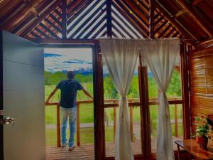 mężczyzna stojący na ganku patrzący przez okno w obiekcie HOTEL CAMPESTRE LA ISLA w mieście Villavieja