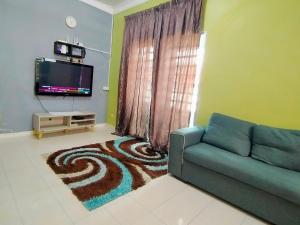 a living room with a couch and a television at RIZQI HOMESTAY Sungai Siput with Wifi! Islamic Guest Only! in Kampong Rimba Panjang