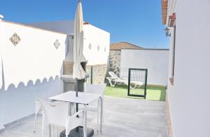 a patio with white chairs and a table and an umbrella at Chalet La Higuerita in Conil de la Frontera