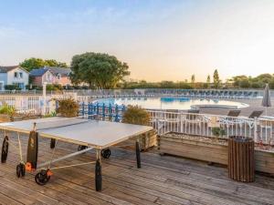 eine Tischtennisplatte auf einer Terrasse neben einem Pool in der Unterkunft "ÉPHÉ'MER TURQUOISE" Appartement-5 pers-vue piscines-village vacances in Talmont