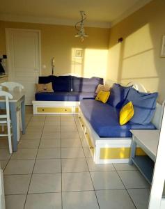 Schlafzimmer mit einem Bett mit blauer Bettwäsche und gelben Kissen in der Unterkunft "ÉPHÉ'MER TURQUOISE" Appartement-5 pers-vue piscines-village vacances in Talmont