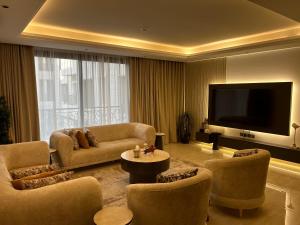 un soggiorno con divano, TV e sedie di Two-Bedroom Apartment a Riyad
