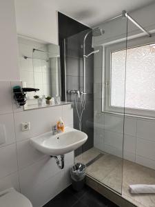 a white bathroom with a sink and a shower at Pension Zwei A in Leverkusen