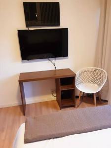 a room with a desk with a tv and a chair at Studio116-completo, confortável, amplo, prático in Brasilia