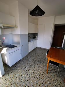 una cucina con mobili bianchi e un tavolo di legno di Beau T1 Spacieux, Proche Centre et lac ad Annecy
