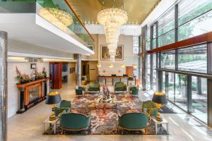 a lobby with a table and chairs and a fireplace at Hotel Divinus in Debrecen