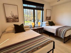 two beds in a room with a window at Verbier New Luxurious Condo 2bdrm spa-pool-sauna in Mont-Tremblant