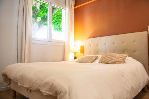 a bedroom with a large white bed with a window at Cosy house near the Parc Bordelais in Bordeaux