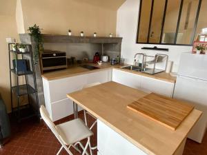 Il comprend une cuisine équipée d'une table en bois et d'un réfrigérateur blanc. dans l'établissement NEW Grand Studio Plein centre Clermont-Ferrand, à Clermont-Ferrand