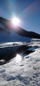 un campo cubierto de nieve con el sol reflejándose en el agua en Pension & Appartament Anna, en Predoi