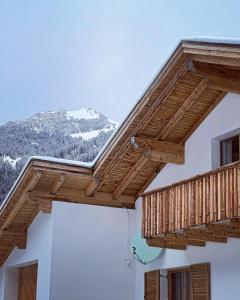 un balcón de madera en un edificio con una montaña cubierta de nieve en Spitzen Blicke – Apartments en Silbertal