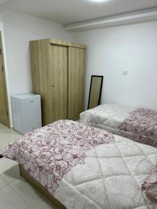 - une chambre avec 2 lits et des couvertures roses et blanches dans l'établissement Karak Plaza Apartments, à Al-Karak