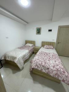 two beds sitting in a room with at Karak Plaza Apartments in Kerak