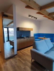 sala de estar con sofá azul y cocina en Aquarius Stawy 10, en Grodzisk Mazowiecki
