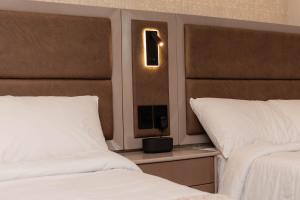 a bedroom with two beds and a light on the wall at Amari Living Suites in Barranquilla