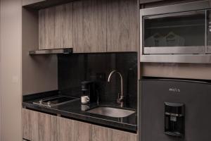 a kitchen with a sink and a microwave at Amari Living Suites in Barranquilla