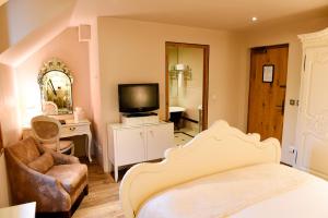 ein Schlafzimmer mit einem Bett, einem TV und einem Stuhl in der Unterkunft Glenskirlie Castle Hotel in Banknock