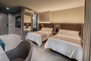 Habitación de hotel con 2 camas y espejo en Amari Living Suites, en Barranquilla