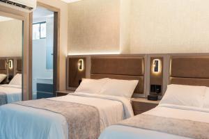 a hotel room with two beds and a mirror at Amari Living Suites in Barranquilla +28 photos