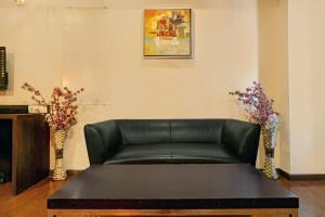 un sofá de cuero negro en una habitación con flores en Collection O Hotel Mapple by green leaves, en Pune
