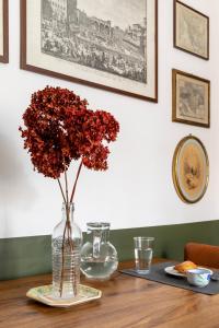 un vase rempli de fleurs rouges assises sur une table dans l'établissement Colosseo Apartment- Heart of Rione Monti, à Rome