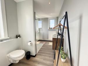 a bathroom with a toilet and a glass door at Loft Monaco - Ruime vakantieloft in De Panne