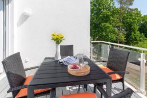 a black table with orange chairs on a balcony at Apartment "Haffliebe" - Haffresidenz in Garz