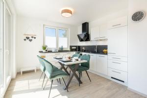 a kitchen with a table and green chairs at Apartment "Haffliebe" - Haffresidenz in Garz