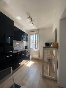 a kitchen with black cabinets and a wooden floor at Studio avec terrasse à Deauville in Deauville