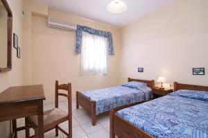 a bedroom with two beds and a table and a desk at Sofia's Studios in Asos