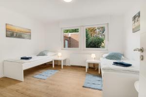 - un salon blanc avec 2 lits et une fenêtre dans l'établissement Stilvoller Bungalow in Selm-Cappenberg, à Selm