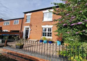 a brick house with potted plants in front of it at The Kenilworth Spacious 2-bedroom w/ Free Parking by Sublime Stays in Spon End